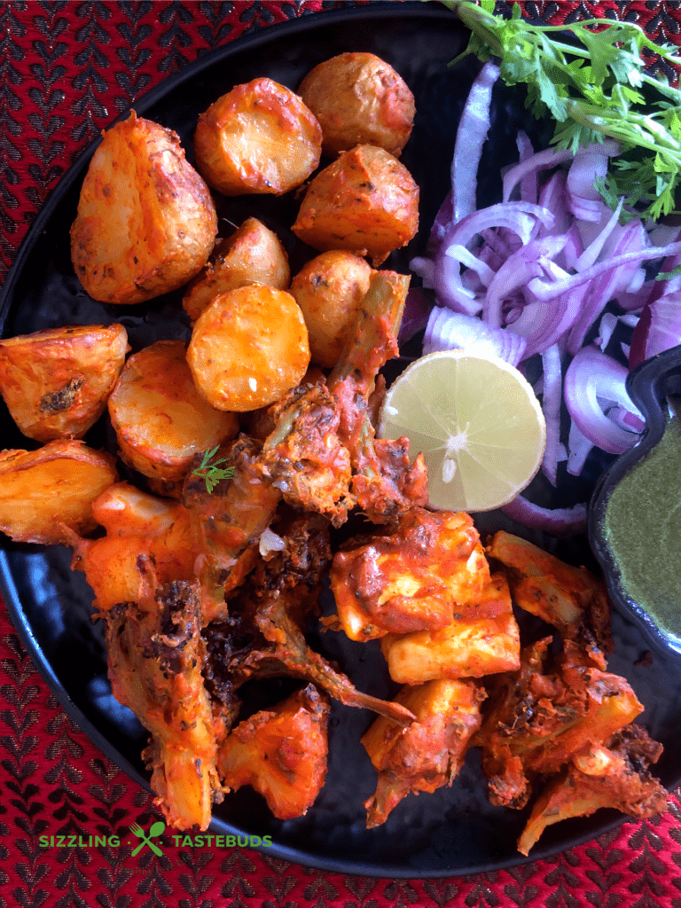 Tandoori Aloo is a gluten free snack made with marinated baby potatoes baked in a Tandoor (or an oven) and served with a spicy-tangy coriander mint sauce and a salad on the side.