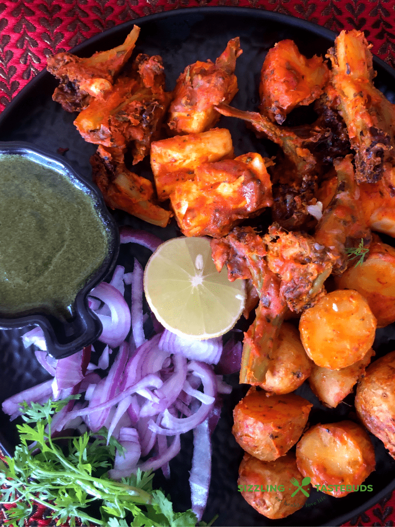 Tandoori Aloo is a gluten free snack made with marinated baby potatoes baked in a Tandoor (or an oven) and served with a spicy-tangy coriander mint sauce and a salad on the side.